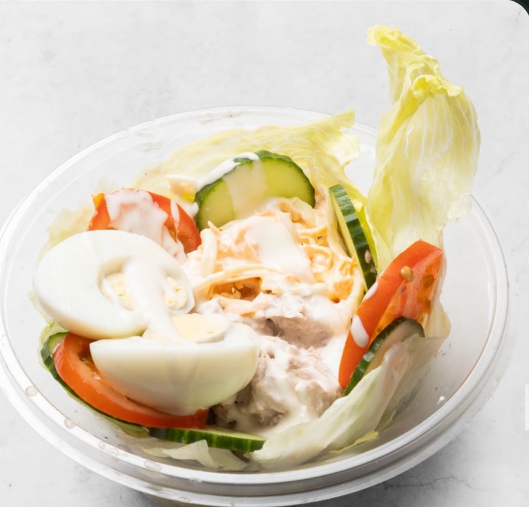 A salad bowl with egg, tomato, cucumber, coleslaw and tuna