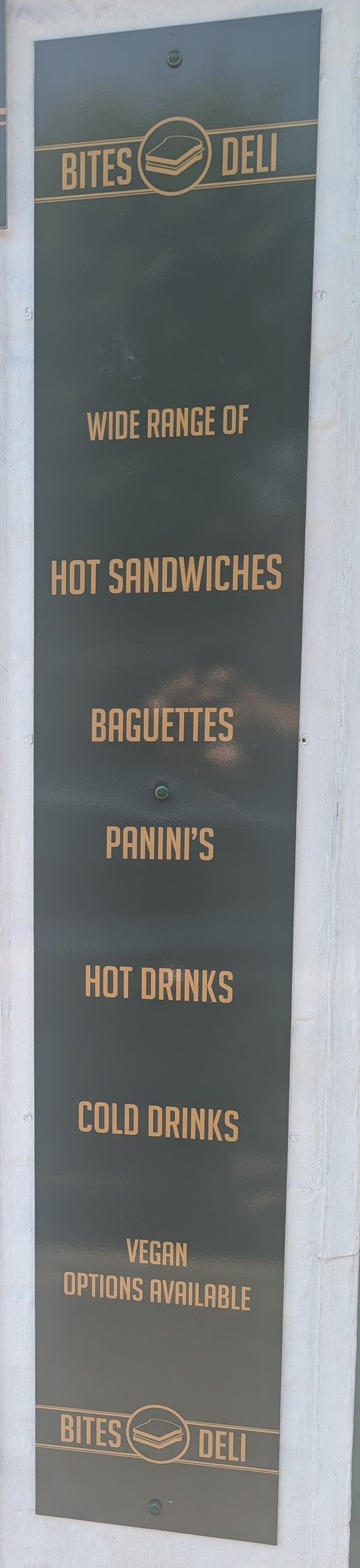 The Bites Deli sign board outside the shop, listing hot sandwiches, baguettes, paninis, hot drinks, cold drinks and vegan options